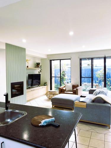 a kitchen and living room with a couch and a table at Anchor Ocean Grove - Fireplace, Wineries, Cafes, Bars, Surf in Ocean Grove
