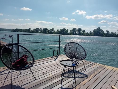 two chairs sitting on a dock next to a body of water at Splav ostruznica in Belgrade