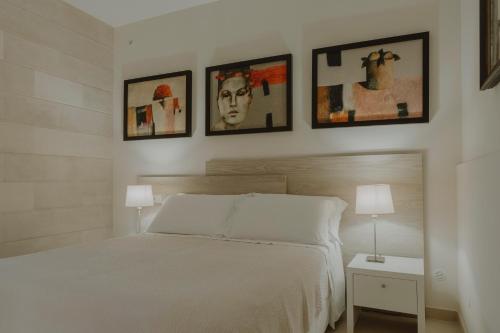 1 dormitorio con 1 cama blanca y 4 cuadros en la pared en Villa Patrizia Salento Art & Room en Porto Cesareo
