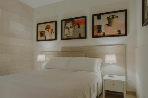 a bedroom with a white bed and four pictures on the wall at Villa Patrizia Salento Art & Room in Porto Cesareo