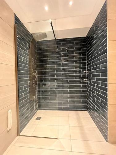 a bathroom with a shower with black tiles at Endless Bleu Villa Andros Island in Apróvaton