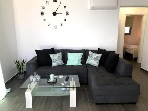 a living room with a couch and a clock on the wall at Endless Bleu Villa Andros Island in Apróvaton