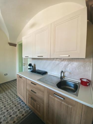 a kitchen with white cabinets and a sink at Tra i due ponti in Bosa