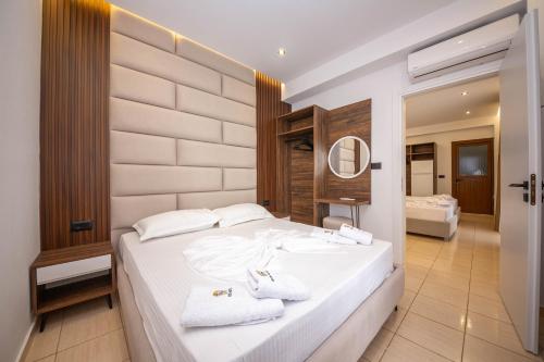 1 dormitorio con 1 cama blanca grande y toallas. en Hotel New Crystal, en Ksamil