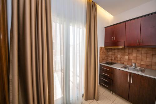 una cocina con fregadero y una ventana con cortinas en Hotel New Crystal, en Ksamil