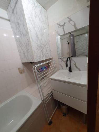 une salle de bain blanche avec un lavabo et une baignoire dans l'établissement Apt T2 bis, 5p secteur Richelieu avec terrasse, piscine, tennis, parking privé, au Cap d'Agde