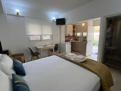 a bedroom with a large white bed and a kitchen at Vaso Studios in Vathi, Ithaka