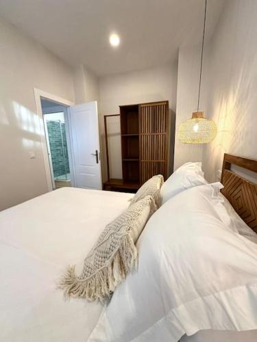 1 dormitorio con 1 cama con sábanas blancas y lámpara en Main Beach - Lavalle Apartamentos, en Loredo