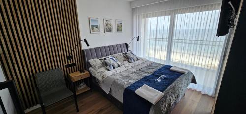 a bedroom with a bed and a large window at Solaris Darłówko Premium Emilia Strupiechowska in Darłowo