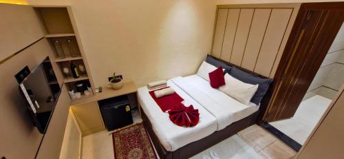 a small bedroom with a bed with red pillows at The Vacation Villa in Agra