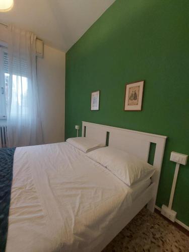 a bedroom with a white bed with a green wall at Sauro 43 in Pisa