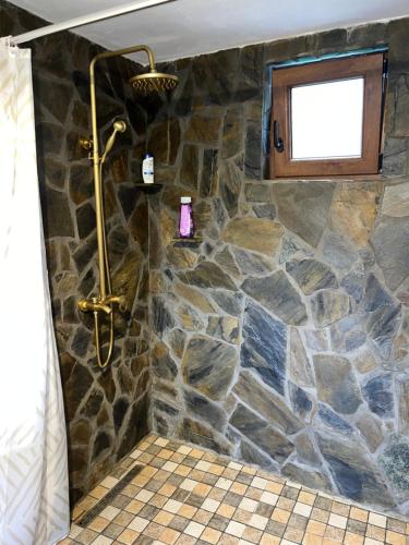 a bathroom with a stone shower with a window at Wild Glamping Cornereva in Cornereva