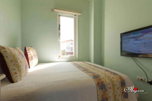 a bedroom with a bed with a flat screen tv at Kenting Avignon in Hengchun South Gate