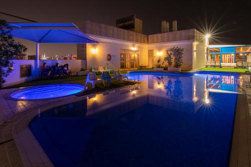 a swimming pool at night with lights at Corp Hotel Apartments and Spa in Doha