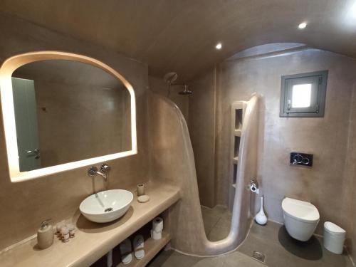 a bathroom with a sink and a shower with a mirror at Amphitrite Suites Santorini in Vóthon