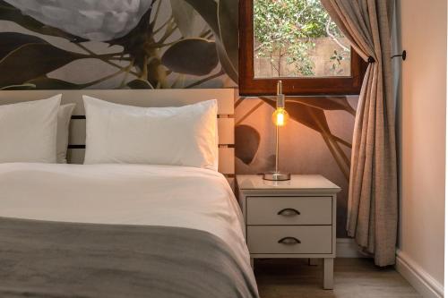 a bedroom with a bed and a window and a lamp at Sixteen Guesthouse on Main in Hermanus