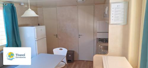 a small kitchen with a table and a refrigerator at Comfortable campsite-chalet G12 Tuscany near sea in Viareggio