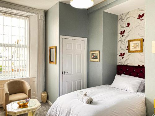 um quarto com uma cama e uma cadeira em The Trinity Lodge - Self Serviced em West Bromwich