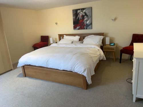 1 dormitorio con 1 cama grande y 2 sillas en Cozy 3 bedroom bungalow in rural location en Ashwell