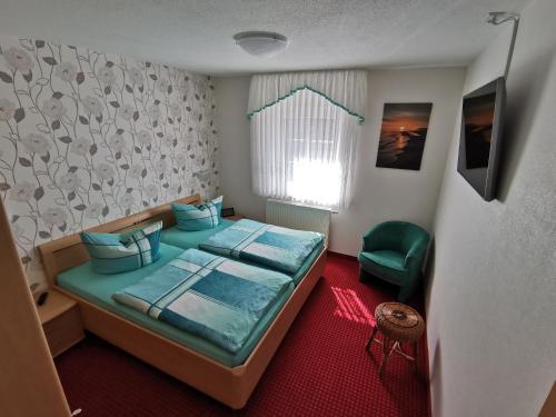 een kleine slaapkamer met een bed en een groene stoel bij Ferienwohnung Hidde in Ostseebad Koserow