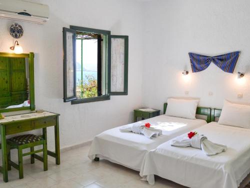 two beds in a room with a desk and a mirror at Hotel Finiki View in Foinikion