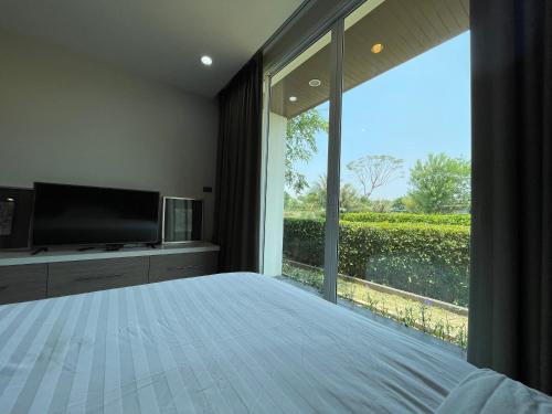 a bedroom with a large window and a television at Momento Poolvilla Khaoyai in Ban Khanong Phra Nua