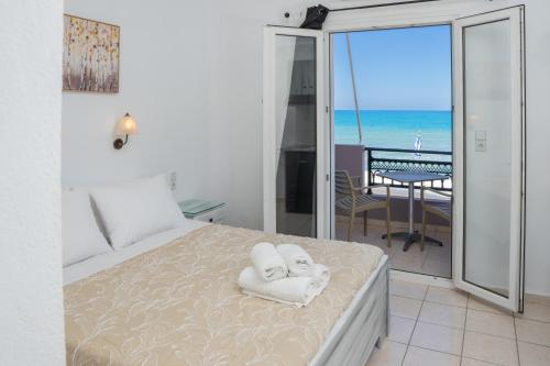 a bedroom with a bed and a balcony with the ocean at ARTEMIS beach studios in Kalamaki Heraklion