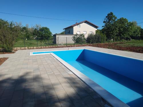 een blauw zwembad in een tuin met een huis bij Villa Ella in Ljubuški