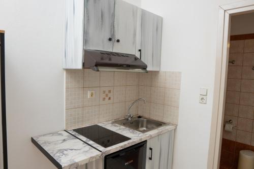 a kitchen with white cabinets and a sink at ARTEMIS beach studios in Kalamaki Heraklion
