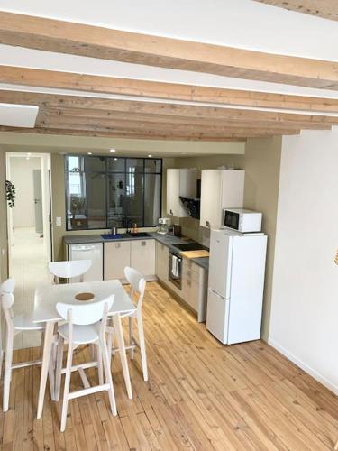 une cuisine avec une table, des chaises et un réfrigérateur dans l'établissement De ville en vignes, à Villefranche-sur-Saône