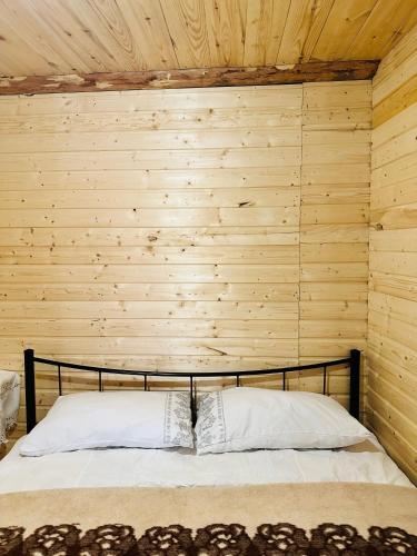 a bed in a room with a wooden wall at ზაზას სახლი in Dart'lo