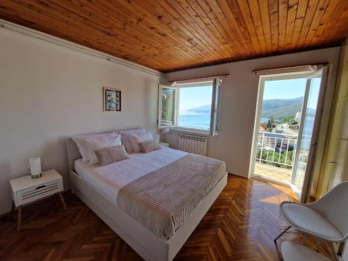 ein Schlafzimmer mit einem Bett und zwei Fenstern in der Unterkunft Apartment Nadija in Rabac