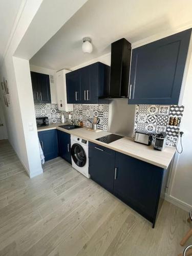une cuisine avec des armoires bleues et une machine à laver dans l'établissement Appartement 1 chambre proche Gare et Centre Ville, à Poissy