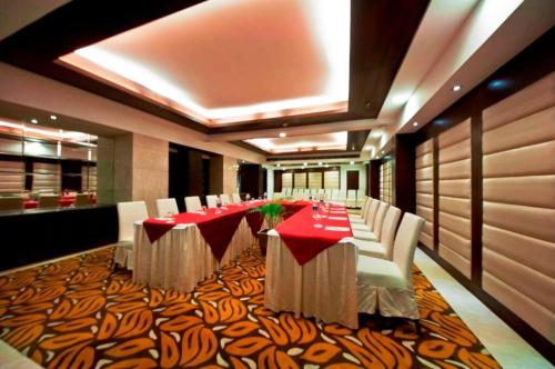 a dining room with a long table and white chairs at Hotel Grenville in Gurgaon