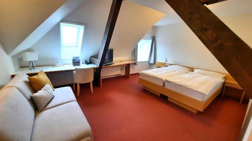 1 dormitorio en el ático con 2 camas y escritorio en Hotel Promenade en Schaffhausen