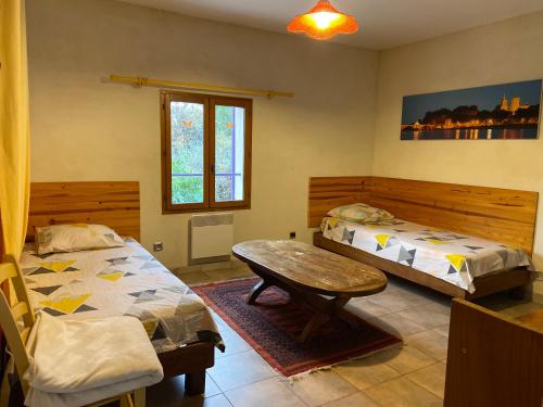une chambre avec deux lits et une table dans l'établissement L'Ile Aux mimosas, à Vaison-la-Romaine