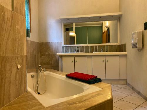une salle de bain avec une grande baignoire avec une serviette rouge dessus dans l'établissement L'Ile Aux mimosas, à Vaison-la-Romaine