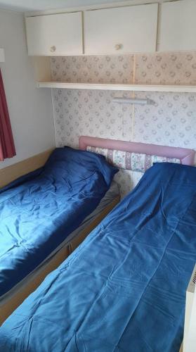 twee bedden in een kleine kamer met blauwe lakens bij Pigi nakvynė Rokiškyje in Rokiškis