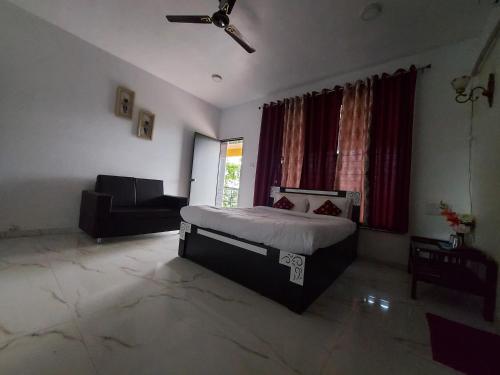 a bedroom with a bed and a couch and a window at The Four Winds House in Mahirāvani