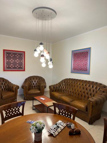 a living room with brown leather couches and a table at Chiaro di Luna Guest House in Roccella Ionica