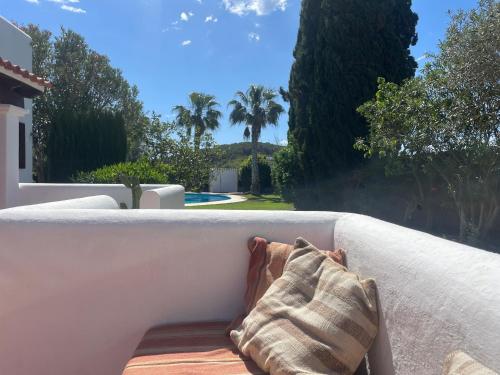 a couch with a pillow sitting on a patio at Authentic Villa with amazing pool in Santa Gertrudis de Fruitera