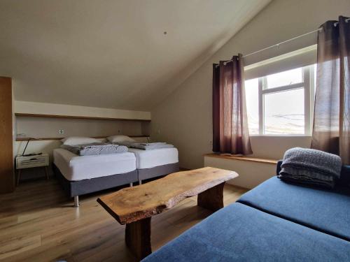 een slaapkamer met 2 bedden en een houten tafel bij Svansholl Apartments in Kaldrananes