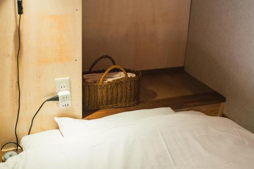 a bedroom with a bed and a basket on the wall at Raicho Onsen Inn in Matsumoto