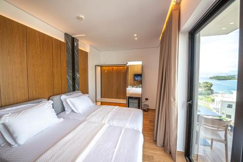 a bedroom with a large white bed with a large window at Nobbu Hotel Ksamil in Ksamil