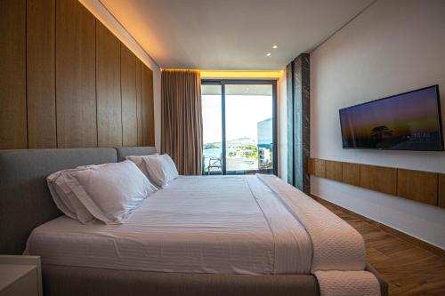 a bedroom with a bed with a tv on the wall at Nobbu Hotel Ksamil in Ksamil