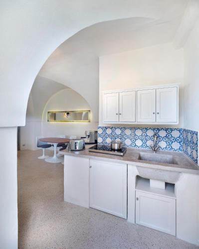 a kitchen with white cabinets and a sink and a table at Masseria Alchimia in Fasano
