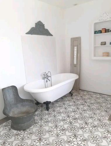 La salle de bains est pourvue d'une baignoire blanche et d'une chaise. dans l'établissement Maison familiale de charme 11 personnes dans le Médoc, à Saint-Germain-dʼEsteuil