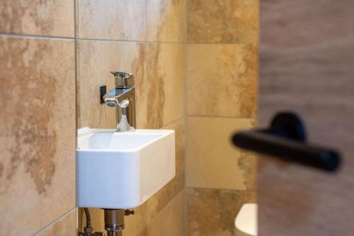 a bathroom with a white sink in a tiled wall at Ferienwohnung Hüttenschnauzer in Pfronten