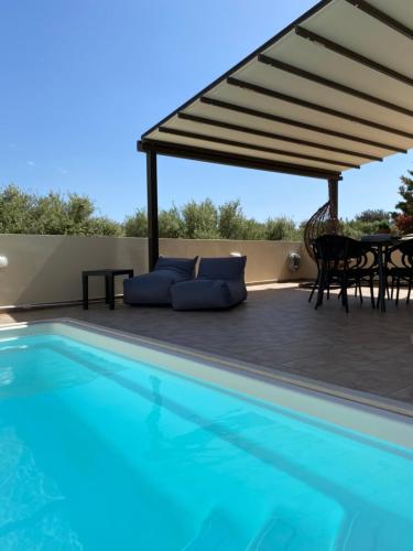 un patio con piscina, mesa y sillas en Villa KIMA Heated Pool en episkopi-heraklion