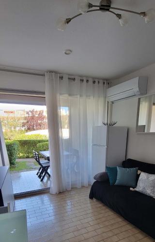 un salon avec un canapé et une grande fenêtre dans l'établissement Studio cabine clim rez-de-jardin résid piscine 150 m plage, à La Grande Motte